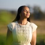 Leya Mnangagwa standing peacefully with eyes closed in golden light, resting in God's presence