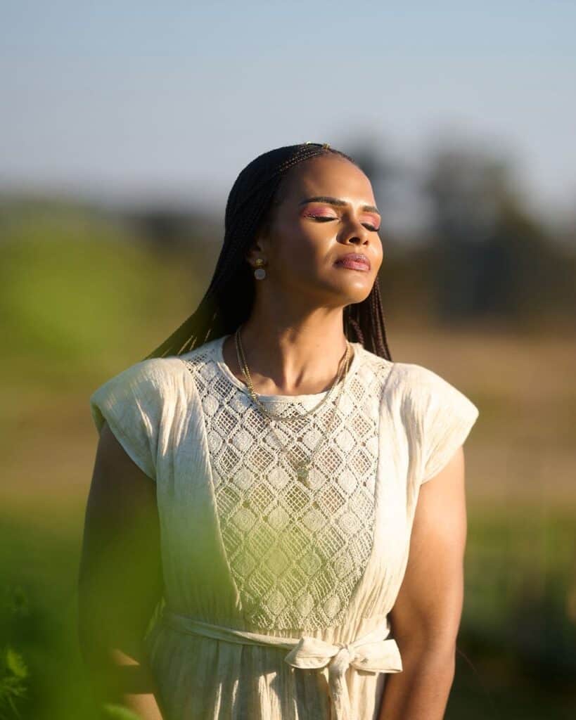Leya Mnangagwa standing peacefully with eyes closed in golden light, resting in God's presence